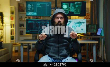 Hacker bearded che indossa una felpa con cappuccio utilizzando la tecnologia aumentata per rompere il firewall governativo. Foto Stock