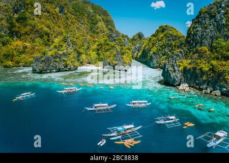 Veduta aerea delle barche turistiche di fronte alla grande Laguna a Miniloc Island, El Nido, Palawan, Filippine. Formazione surreale di crinale calcareo carsico. Foto Stock