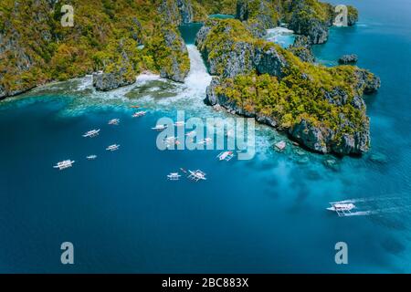 Veduta aerea dell'incredibile isola di Mililoc. Barche turistiche vicino alla grande laguna. El Nido, Palawan, Filippine. Formazione rocciosa carsica surreale. Foto Stock