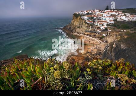 Vista da sogno del pittoresco villaggio Azenhas do Mar ins tramonto con case in gesso sul bordo di una scogliera e la spiaggia sottostante. Luogo di interesse di Sintra, Porto Foto Stock