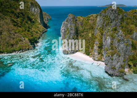 El Nido, PALAWAN FILIPPINE. Vista aerea del mare tropicale Isola di stack con imbarcazioni turistiche ormeggiati alla spiaggia di sabbia bianca. Foto Stock