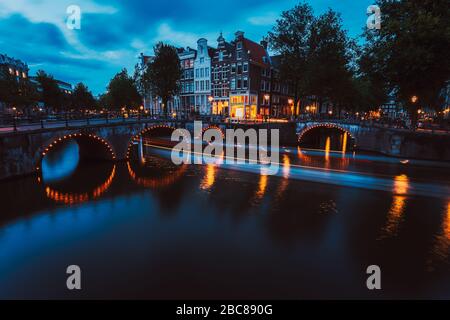 Illuminazione di ponti e percorsi di luce in barca in serata Amsterdam con riflessione nel canale Herengracht. Tipiche case olandesi al tramonto luce, Olanda, Neth Foto Stock