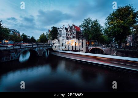 Percorsi leggeri presso i canali Leidsegracht e Keizersgracht ad Amsterdam al tramonto. Scatto a lunga esposizione. Foto Stock