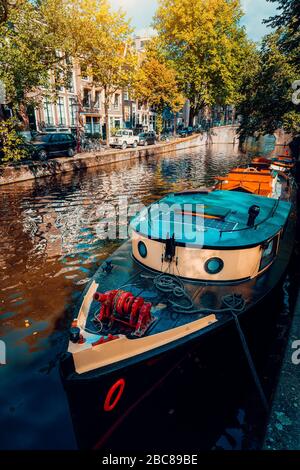 Crociera tradizionale barca ormeggiata ormeggiata in uno dei famosi canali di Amsterdam nella bella e soleggiata giornata autunnale. Foto Stock