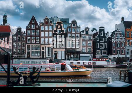 Canale di Amsterdam Singel con case tipiche olandesi e case galleggianti con un bel paesaggio di nuvole sullo sfondo, Olanda, Paesi Bassi. Foto Stock