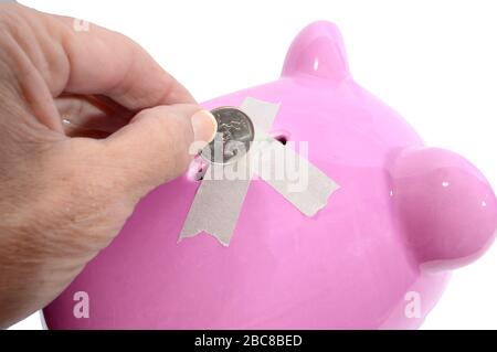 Colpo orizzontale di mano di una donna che cerca di mettere un quarto in una banca rosa piggy slot, ma c'è nastro attraverso di esso. Sfondo bianco. Foto Stock