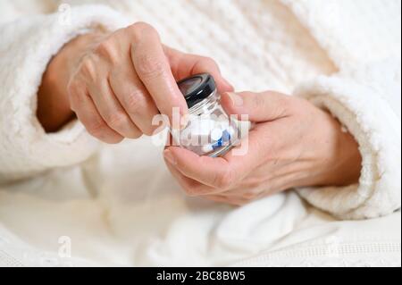 Donna anziana versando pillole dalla bottiglia a portata di mano, vista closeup . Foto Stock