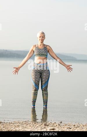 Meditazione IKYA, donna in abbigliamento sportivo allegramente sul lago Foto Stock