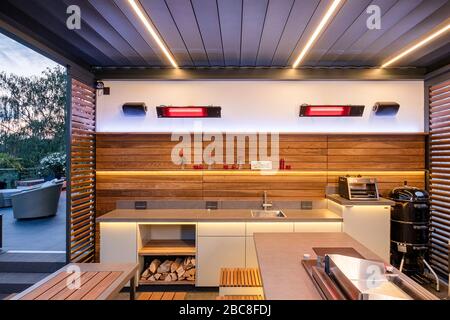 Moderna cucina all'aperto in legno con un caldo concetto di illuminazione Foto Stock