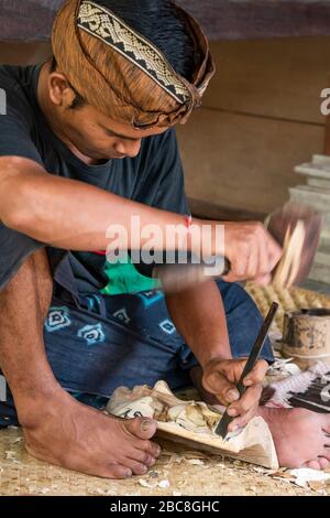 Ritratto verticale di un uomo che carving una maschera di legno a Bali, Indonesia. Foto Stock