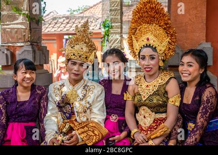 Ritratto orizzontale di una sposa e uno sposo con gli amici in un matrimonio balinese, Indonesia. Foto Stock