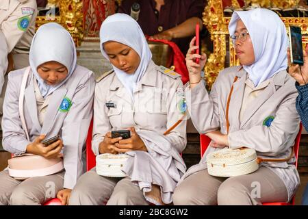 Ritratto orizzontale di un gruppo di ragazze musulmane che usano tutti i loro telefoni a Bali, Indonesia. Foto Stock