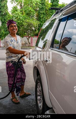 Vista verticale di un uomo che rifornisce la sua auto a Bali, Indonesia. Foto Stock