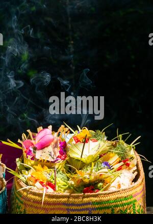 Vista verticale di offerte di fiori, cibo, denaro e incenso utilizzati in una cerimonia a Bali, Indonesia. Foto Stock