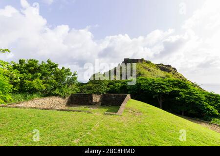 Vista di Fort Rodney sul pendio roccioso erboso che si affaccia sul vasto oceano a Pigeon Island National Landmark a Santa Lucia in una bella giornata di sole Foto Stock