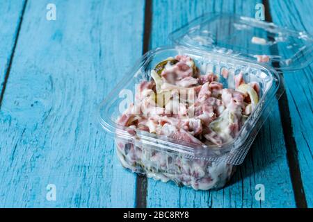 Asporto insalata italiana con maionese, prosciutto e pickle in contenitore di plastica. Piatto tradizionale. Foto Stock