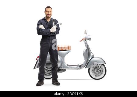 Ritratto a tutta lunghezza di un meccanico che tiene una chiave e sta accanto a uno scooter isolato su sfondo bianco Foto Stock