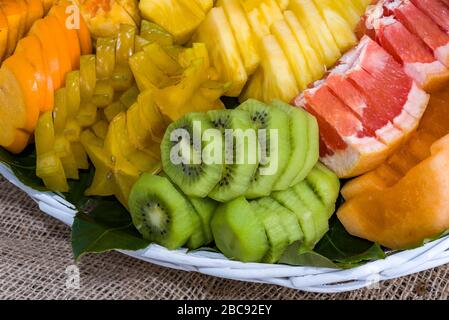 Frutta fresca sana in un cestino sulla tabella frutta a fette in un cestino kiwi ananas fragola. Foto Stock
