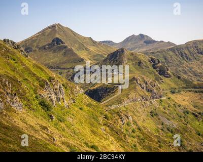 Trekking nel Cantal sulla GR 400, montagne vulcaniche in Francia, stretto sentiero sul Puy Chavaroche. Sullo sfondo Puy Mary a sinistra e Puy Foto Stock