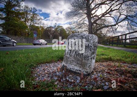 Adare, County Limerick, Irlanda - 10/26/2018: Vecchio contrassegno in pietra che mostra 7 miglia a Rathkeale sulla N21 a Blackabbey. Foto Stock