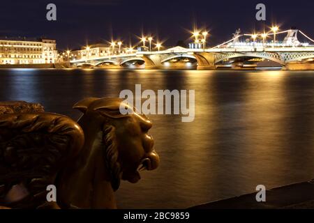 Il Griffin di San Pietroburgo sull'argine del fiume Neva di fronte all'Accademia delle Arti e il ponte Blagoveshchensk come sfondo di notte Foto Stock