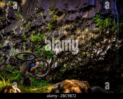 Mountain biker porta la sua bicicletta alla Cascade de Faillitoux. Monts du Cantal, Massif Central, Cantal Francia Foto Stock