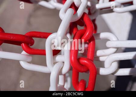 Primo piano di una barriera esterna realizzata con una catena in plastica con maglie rosse e bianche Foto Stock