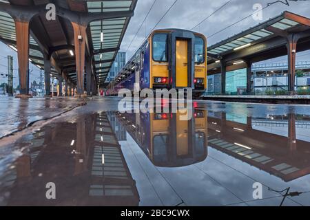 2 Northern Rail classe 153 treni sprinter riflesso in un pudddle alla stazione ferroviaria di Preston Foto Stock