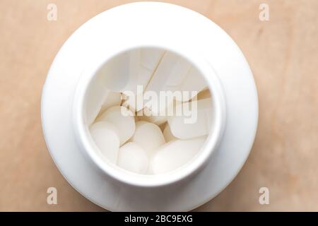 Pillole in un vaso di plastica bianco. Vista dall'alto. Una latta piena di pillole mediche. Foto Stock