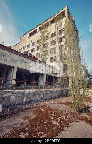 Pripyat, Ucraina - Aprile 25 2019: Iscrizione Hotel Polesie . Edificio abbandonato a Pripyat. Hotel di radiazione irradiata. Alberi giovani germogliano attraverso Foto Stock