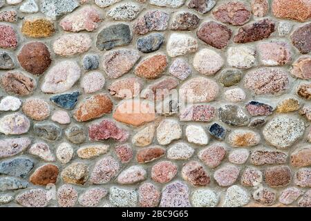 Vista piana di dettaglio di una parete realizzata con pietre diverse. Astratto sfondo di pietra. Foto Stock
