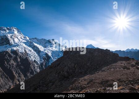 L'escursionista del Parco Nazionale del Monte Cook trionfa su una roccia, Mt Cook, Canterbury, Nuova Zelanda Foto Stock
