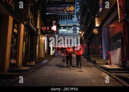 La gente cammina su una strada desertica con pub chiusi durante la crisi di coronavirus.Bars a Hong Kong, sono stati temporaneamente chiusi le loro porte, come governo ordina due settimane di chiusura da 6pm il Venerdì, Aprile 3rd per frenare Covid-19 diffusione. Qualsiasi posto?esclusivamente o pricipalmente usato?per la vendita o la fornitura di alcool sono obbligano a chiudere le relative porte. Foto Stock