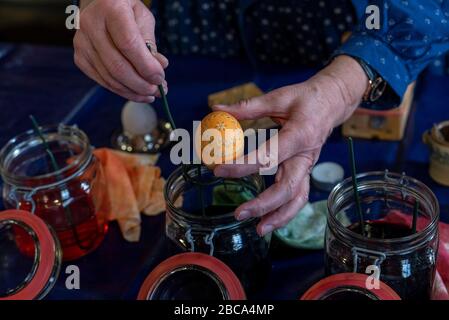 Uovo di Pasqua sorbica, mani di una donna, bicchieri di colore dell'uovo di Pasqua Foto Stock