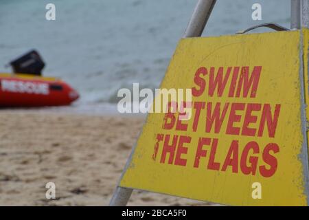 Segnale di avvertimento salvavita per nuotare tra le bandiere su una spiaggia australiana Foto Stock