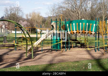 Berks County, Pennsylvania, USA-2 aprile 2020: Parco giochi pubblico chiuso con nastro di attenzione in modo che i bambini non giocano sulle attrezzature per prevenire la diffusione di co Foto Stock