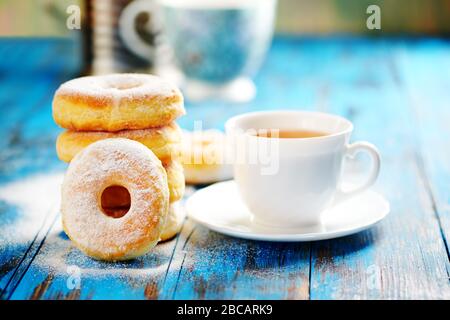 Ciambelle fatte in casa con tè nel pomeriggio uno sfondo di legno blu. Foto Stock