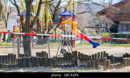 Parco giochi senza bambini. Chiuso con un nastro barriera a strisce rosso - bianco. Vietato entrare a causa delle restrizioni del Coronavirus (Covid-19). Foto Stock