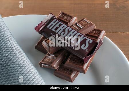 Immagine del cioccolato HERSHEYS a marchio per scopi pubblicitari su un piatto bianco e un tavolo rustico in legno Foto Stock