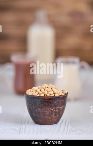 Latte di cioccolato e latte di soia su tavolo di legno bianco (foto con profondità di campo bassa) Foto Stock