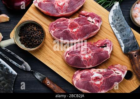 Vista dall'alto dello stinco di agnello fresco tritato sul tagliere con spezie Foto Stock