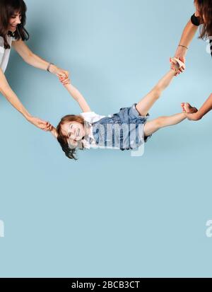 Una ragazza in un jumpsuit denim è tenuto dalle sue gambe e basculante Foto Stock