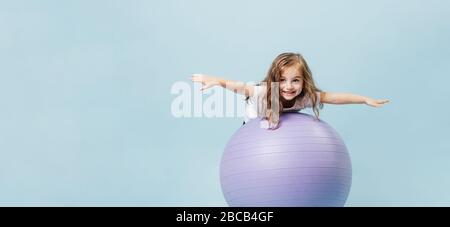 Divertente ragazza riccio-capelli gioca su una palla ginnastica Foto Stock