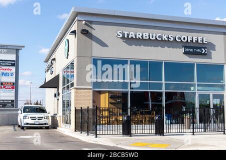 L'auto attende al finestrino drive-through come caffè Starbucks vuoto a causa della pandemia COVID-19, vista nella giornata di sole. Foto Stock