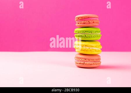 I macaroon multicolore si trovano in un mucchio su un tavolo rosa Foto Stock