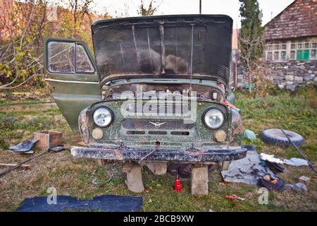 Soviet UAZ SUV su una strada della città. Vetro faro di un vecchio retro russo camion SUV all-Terrain cachi colore . Davanti alla UAZ . Stanno riparando Foto Stock