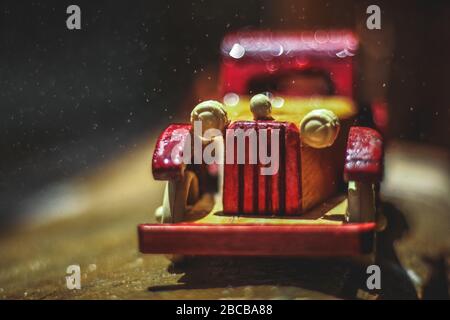 Giocattolo vintage sotto la pioggia sulla strada. Giocattolo per auto in miniatura in pioggia. Auto d'epoca rossa e gialla sotto la pioggia. Pioggia che cade sul giocattolo auto d'epoca si chiude Foto Stock