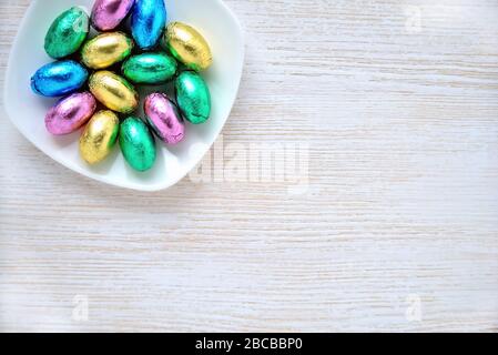 piccole uova di cioccolato in involucri colorati su piattino, posto per iscrizione Foto Stock