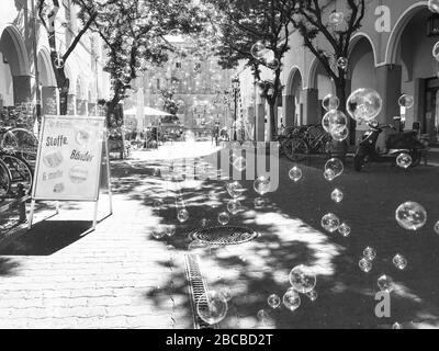 Allegra immagine in bianco e nero di bolle di sapone che si sgorgano attraverso una strada soleggiata della città di Berlino Foto Stock