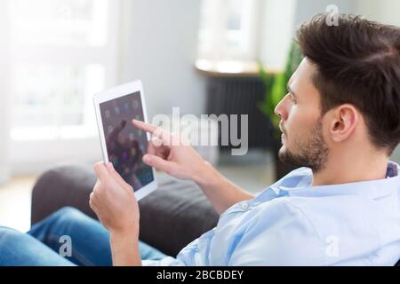 Uomo seduto sul divano con la tavoletta digitale Foto Stock